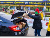 Santa's helper places a turkey in the trunk of the car at an earlier Thanksgiving turkey giveaway