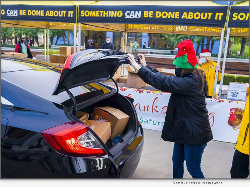 Santas helper places a turkey in the trunk of the car at an earlier Thanksgiving turkey giveaway