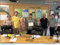 Nate Ward is centered in the image. To his left is the Mayor of Hailey, Martha Burke, along with the city council members. To the far right is Bryson Elsworth, who is Nate’s mentor.